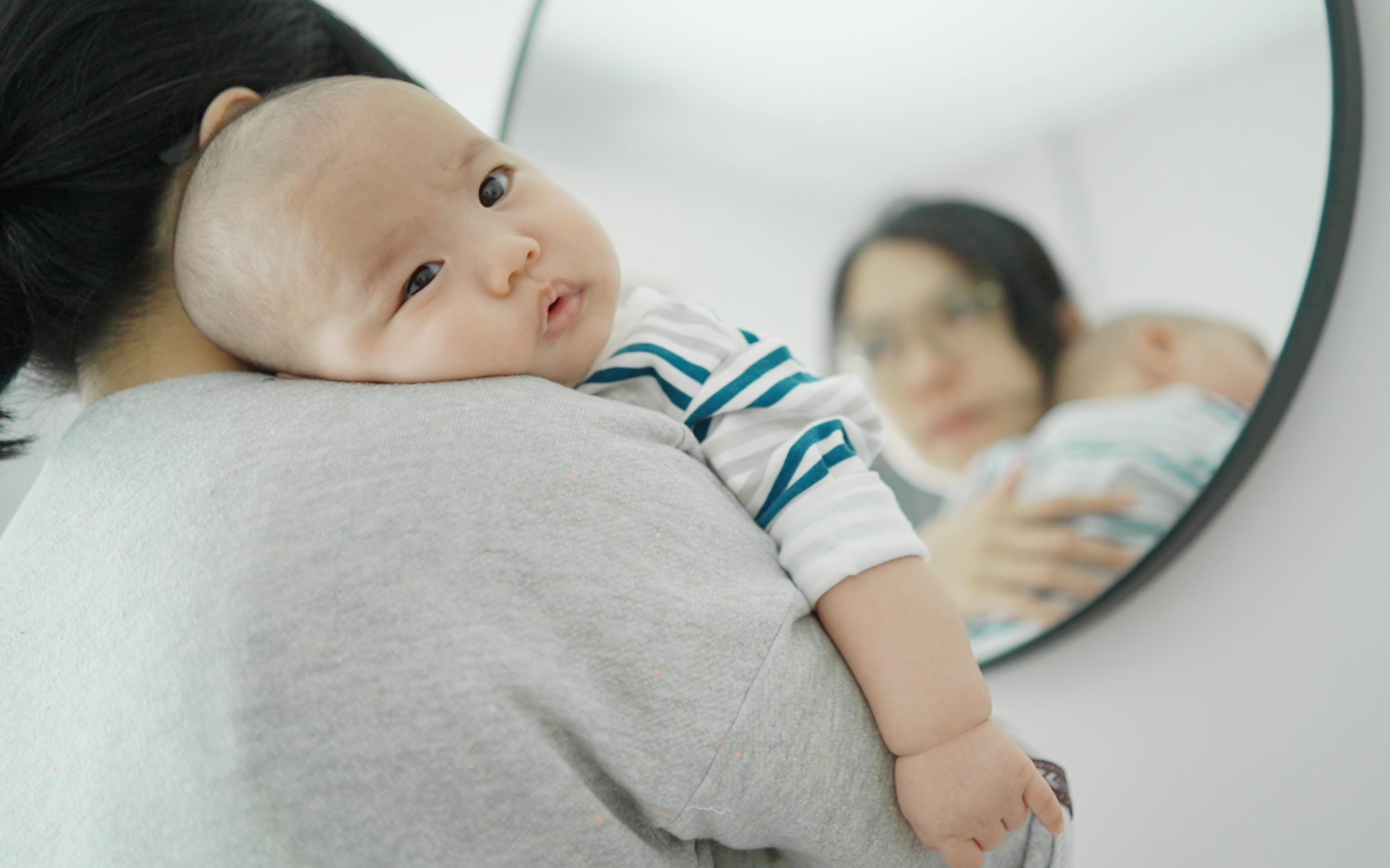 A baby looks over his mother's shoulder